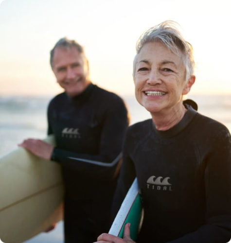 middle aged man and woman holding surf boards